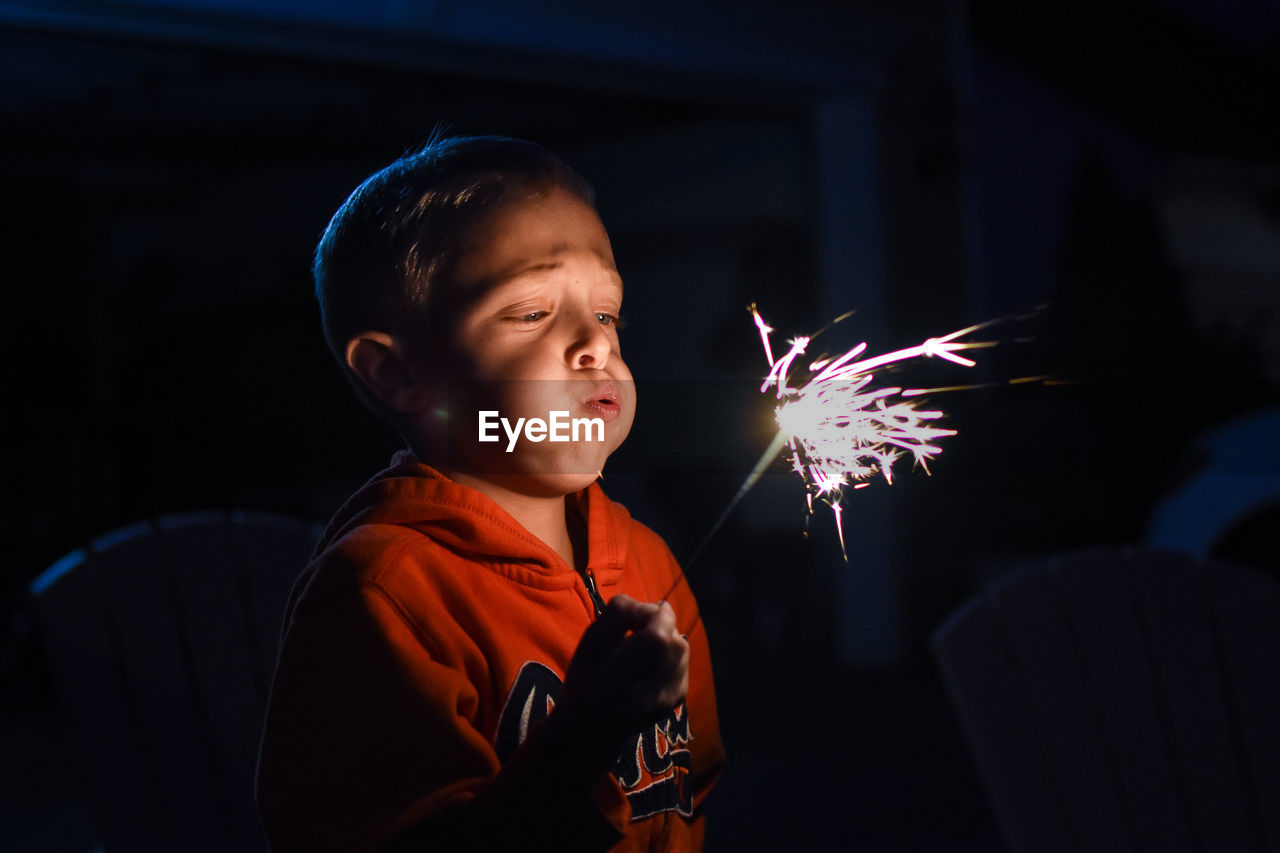 Close-up of boy blowing sparkler