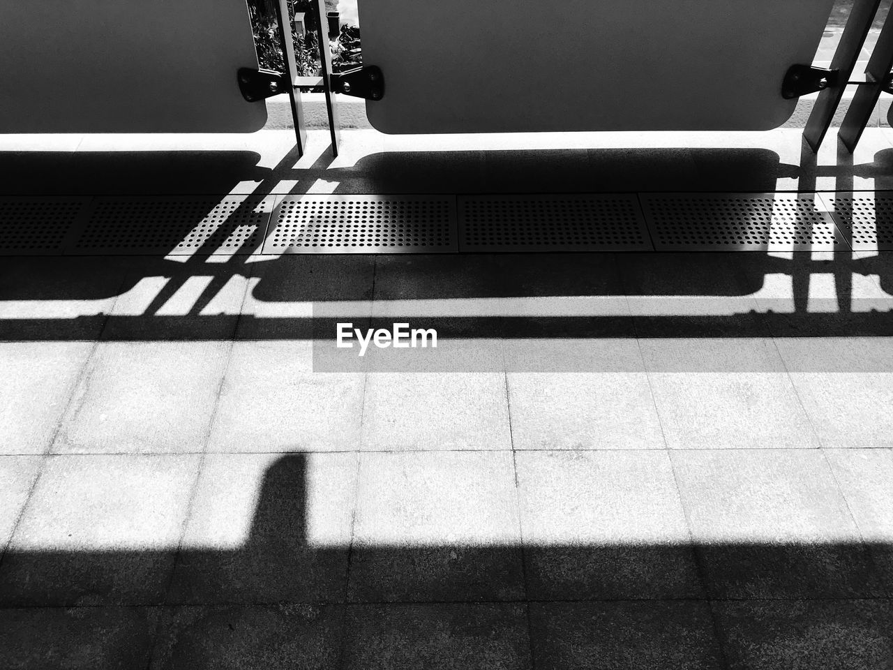 Shadow of railing on sidewalk during sunny day