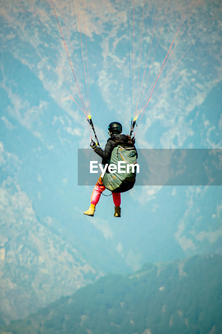 low angle view of woman paragliding against mountain