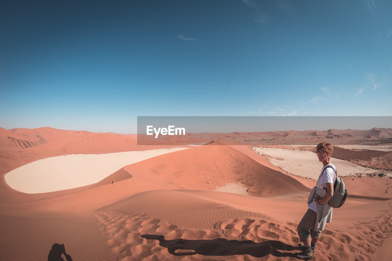 Portrait of female tourist standing at namib desert in naukluft national park during sunny day