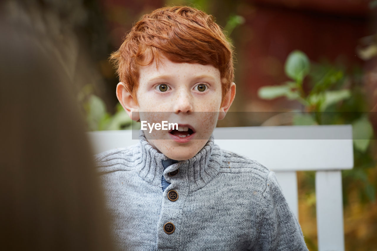 Surprised boy looking away while sitting in yard