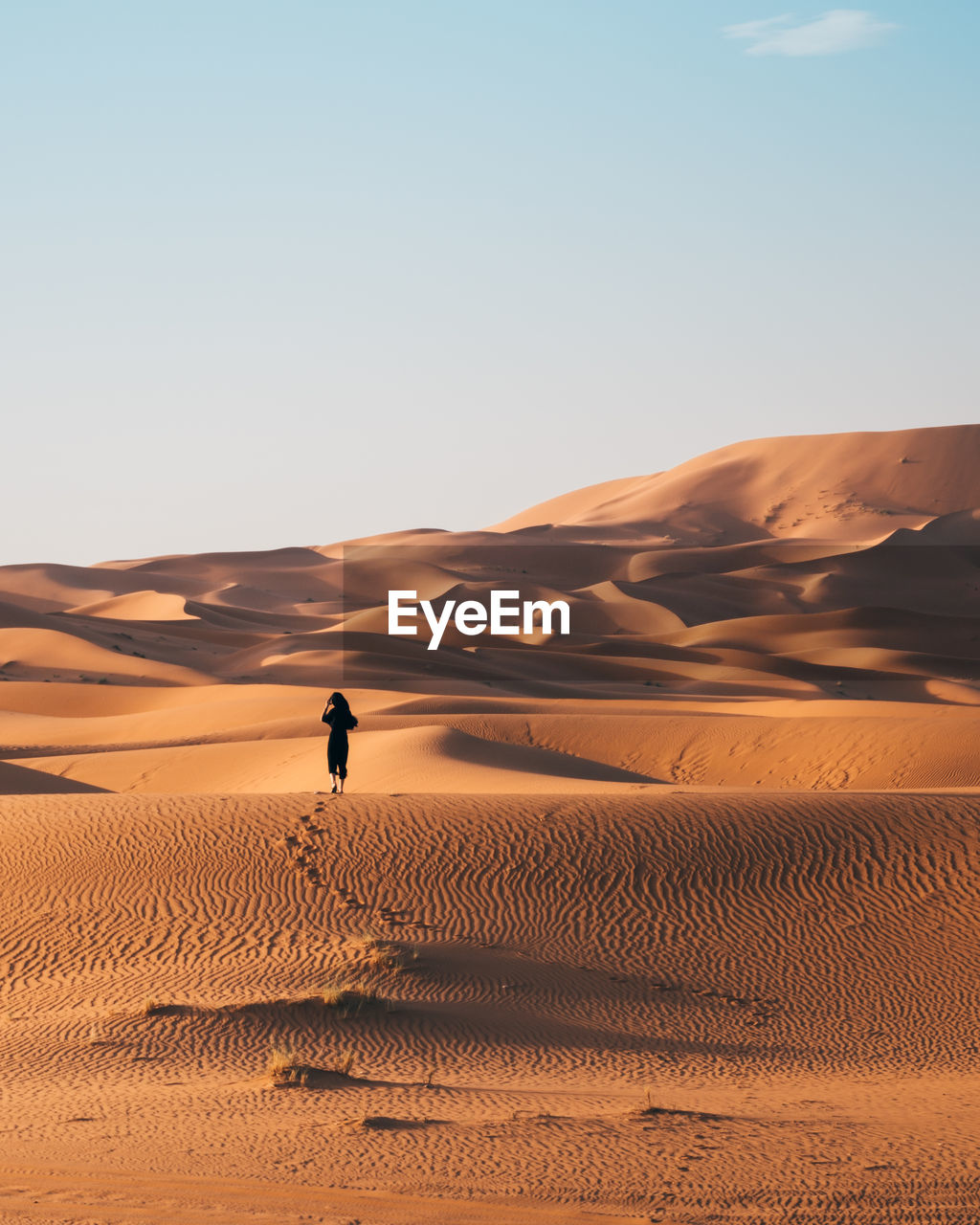 Woman on sand dune in desert against sky