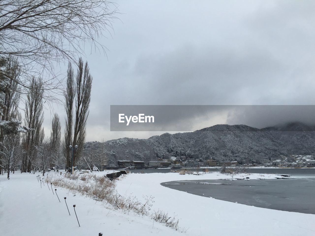 Scenic view of frozen lake by mountains against cloudy sky