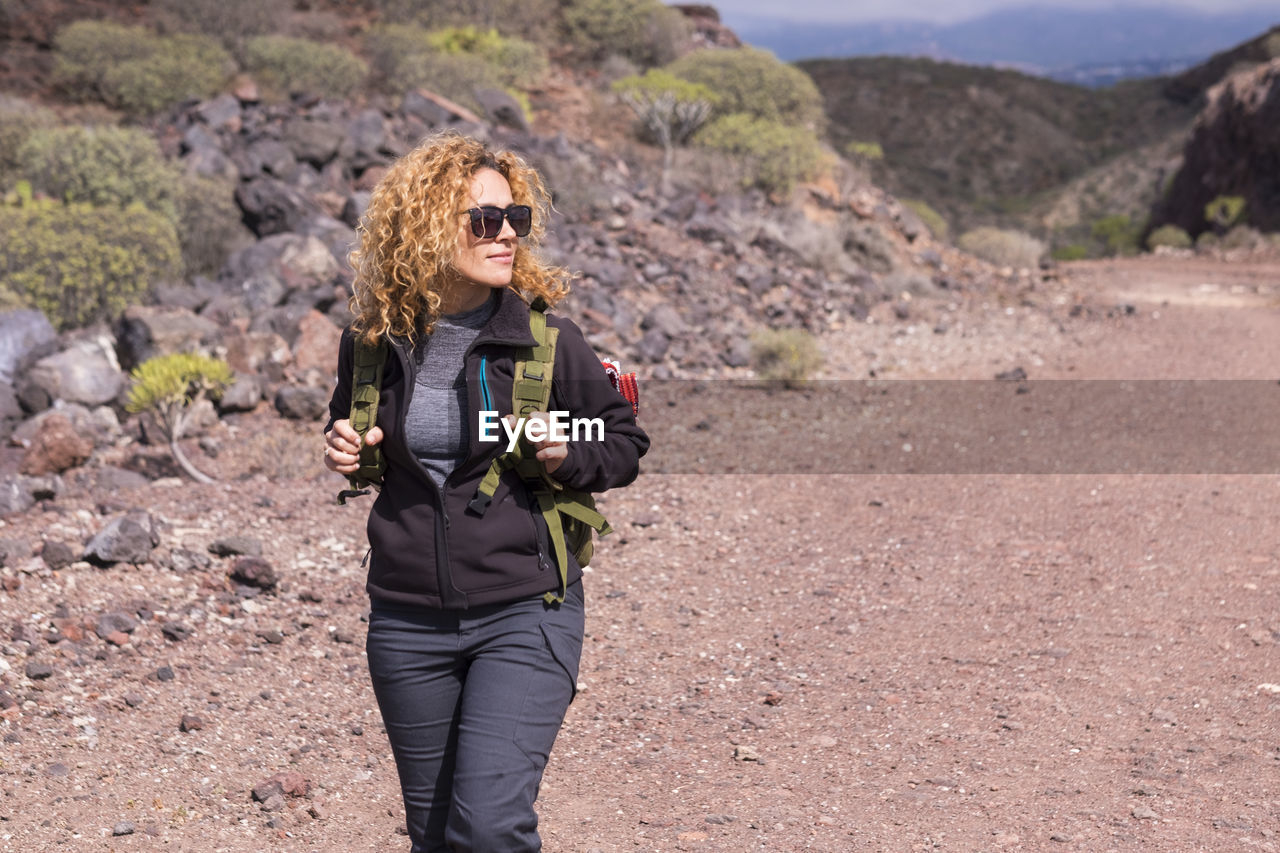 side view of young woman standing against mountain