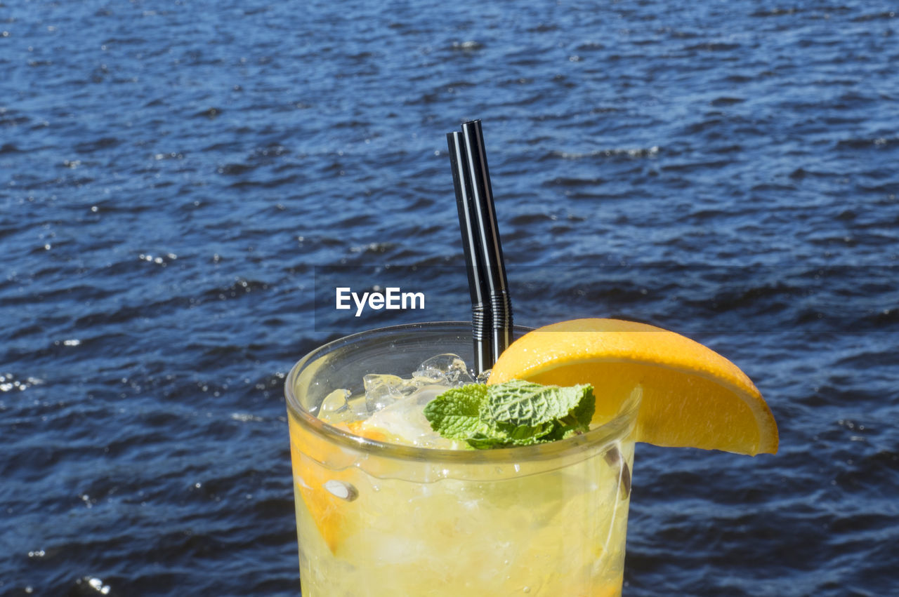 Close-up of lemonade in glasses against sea