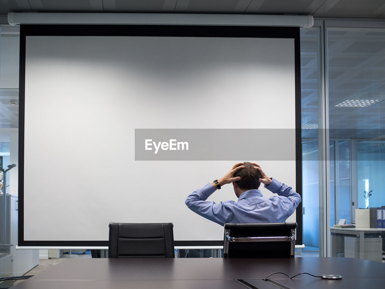 Rear view of businessman with head in hand during meeting in office