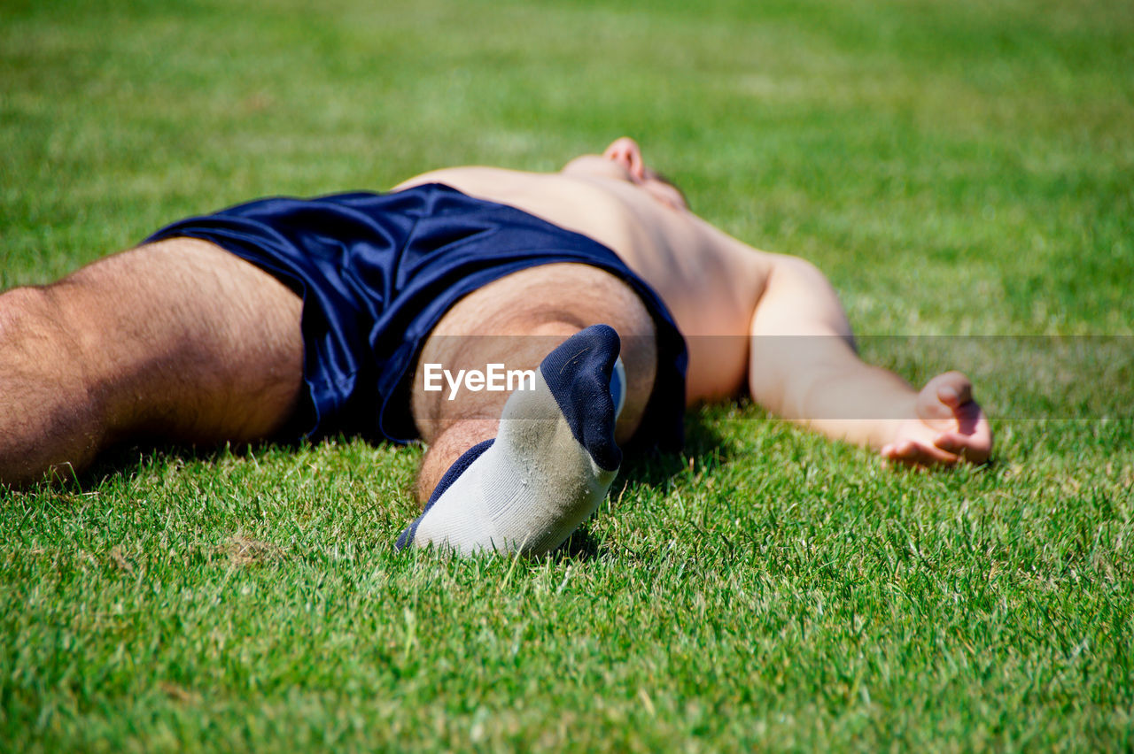 Shirtless soccer player sleeping on field