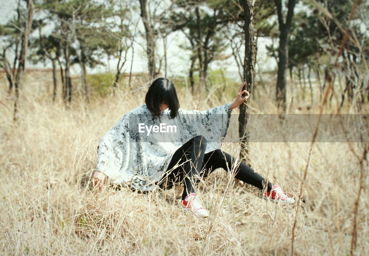 Young woman sitting on grassy field in forest