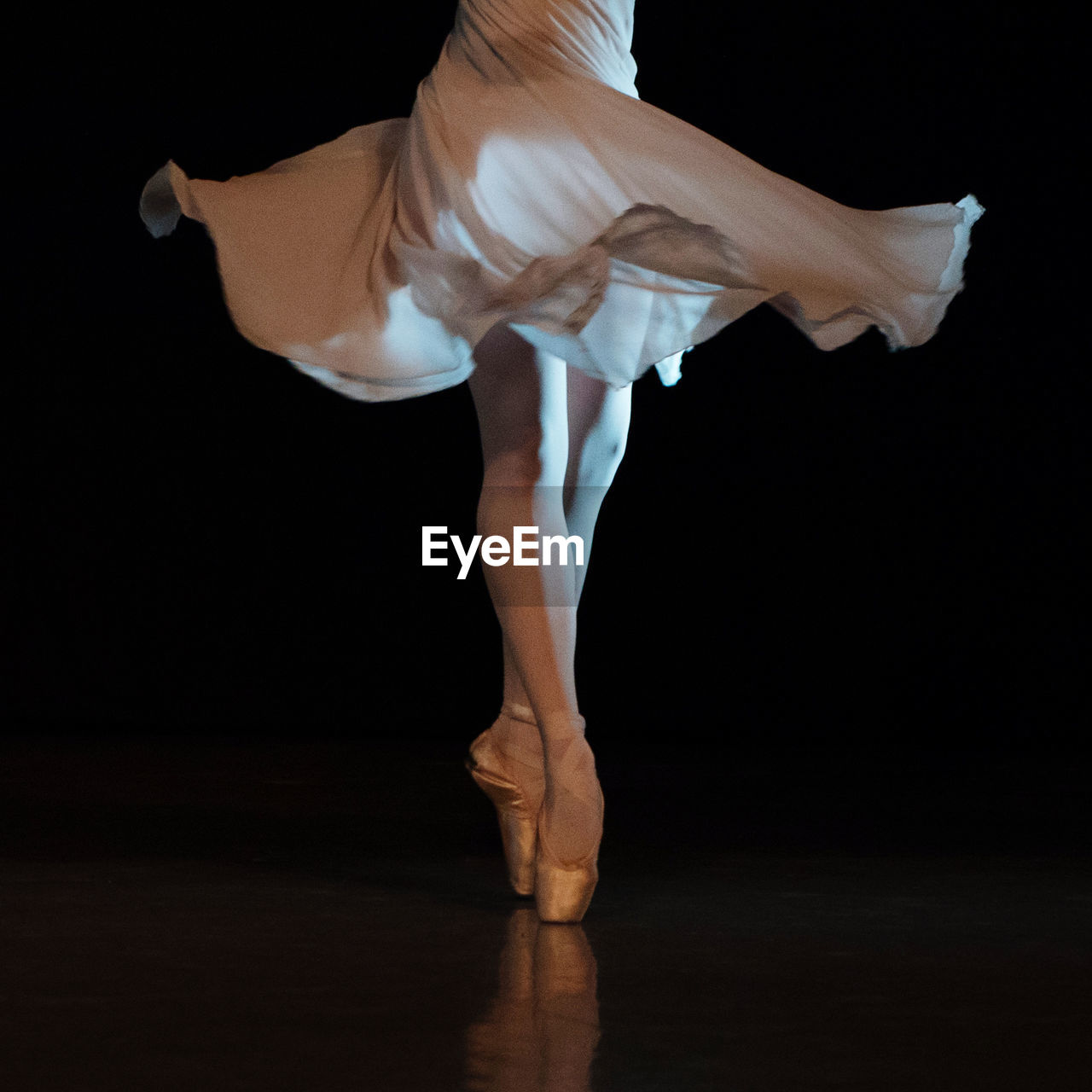 Low section of ballerina dancing against black background