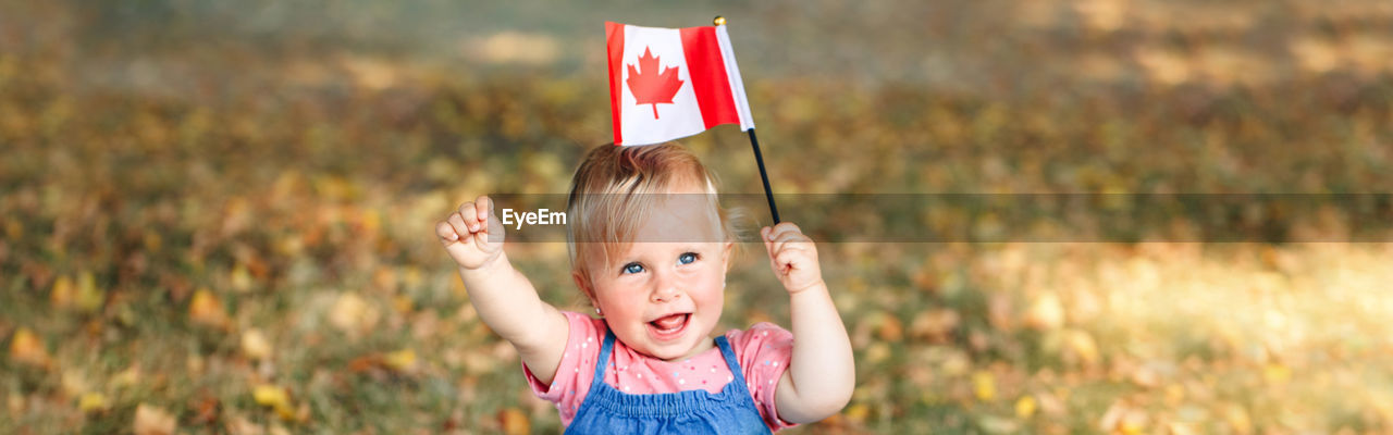 Caucasian baby toddler girl waving canadian flag in park outdoor.  web banner header.