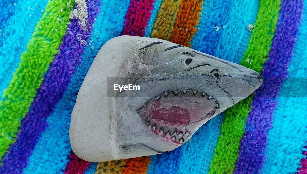 Close-up of shark painted on stone over towel