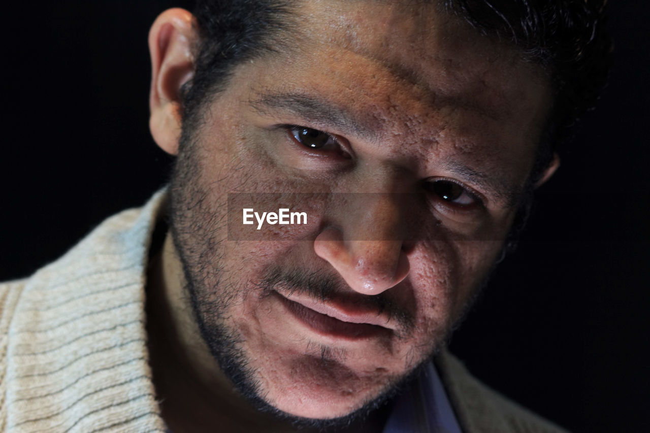 Close-up portrait of man against black background