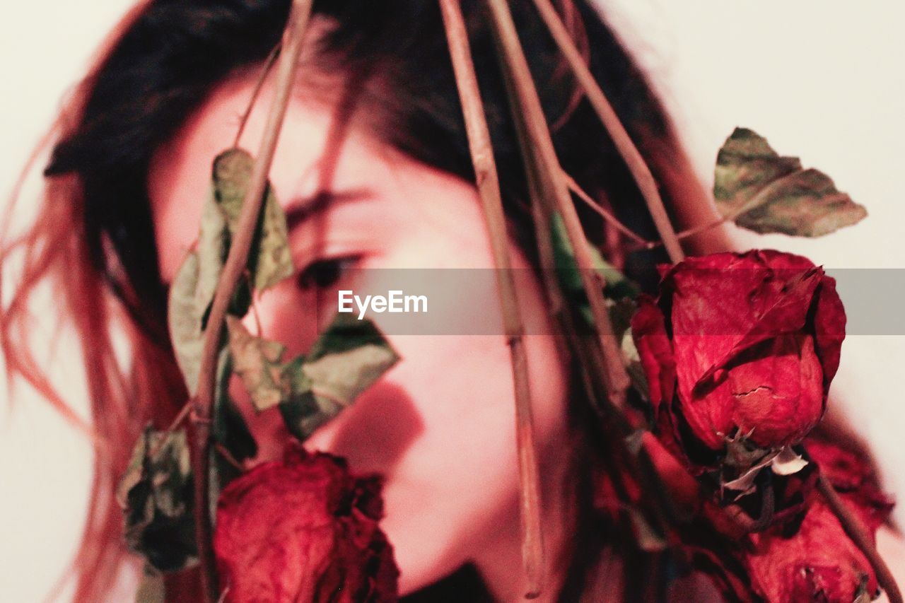 Close-up of woman with red roses at home