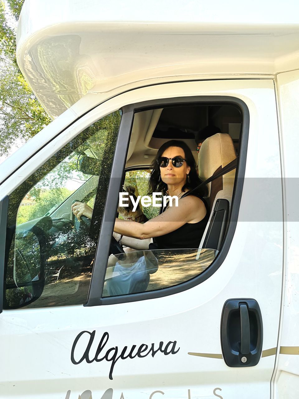 PORTRAIT OF WOMAN IN SUNGLASSES SITTING ON CAR