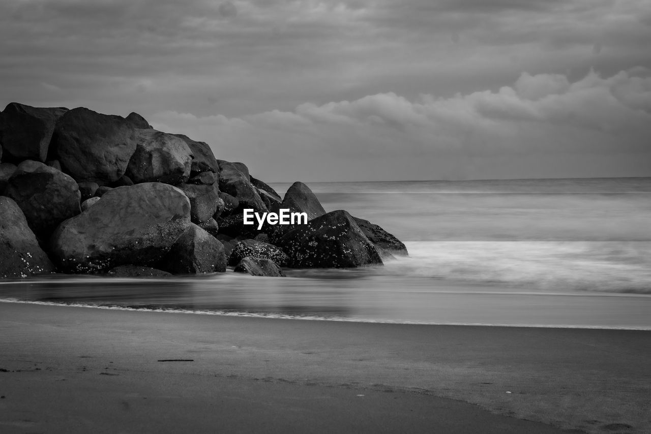 Scenic view of rocks on beach against sky