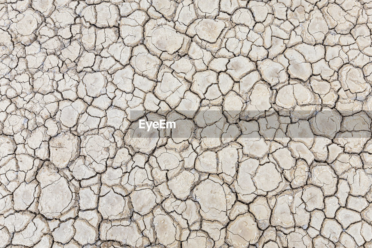 FULL FRAME SHOT OF CRACKED LAND ON DRY GROUND