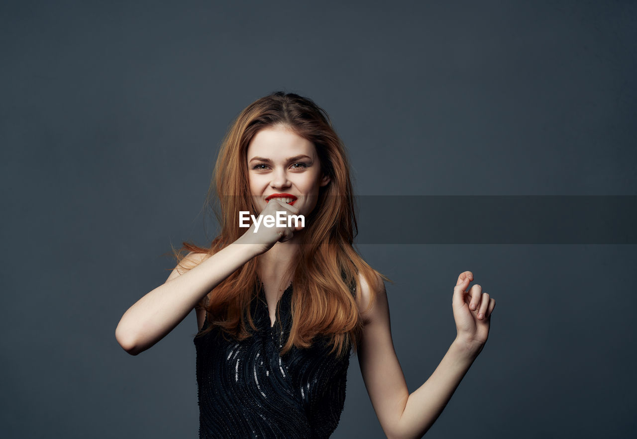 portrait of young woman looking away while standing against black background