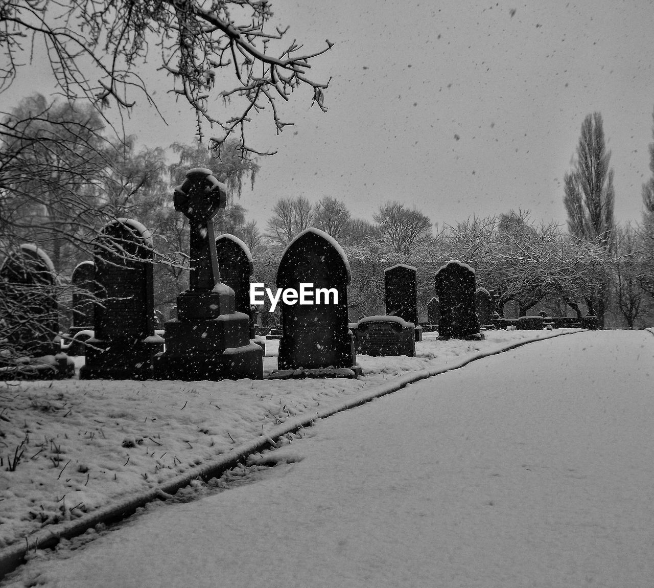 Snow covered cemetery against clear sky