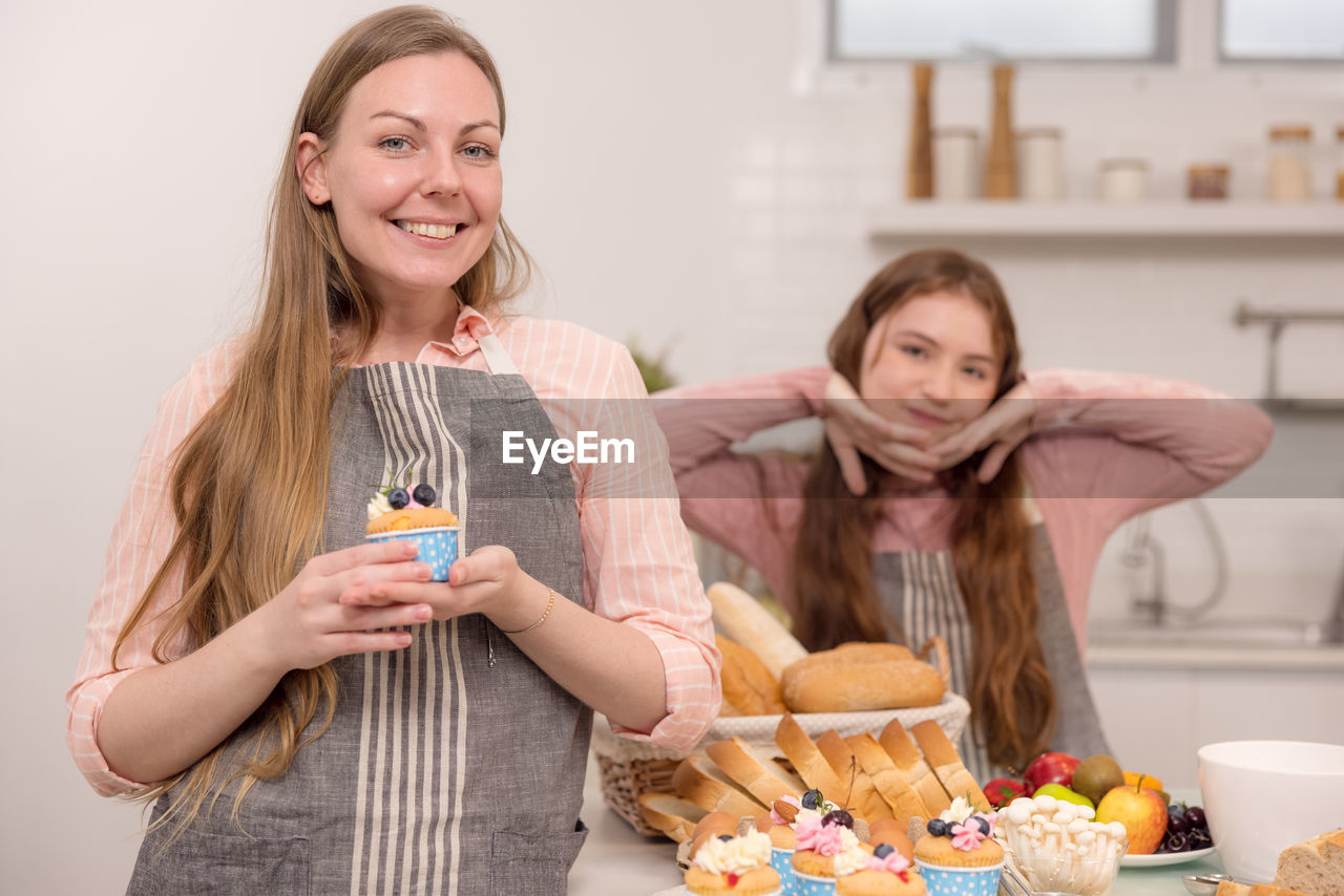 American mother and daughter holding cupcakes and smiling at each other