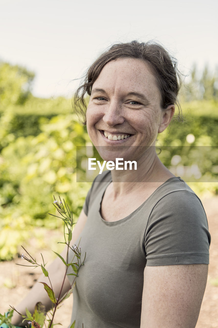 Portrait of happy woman standing at community garden