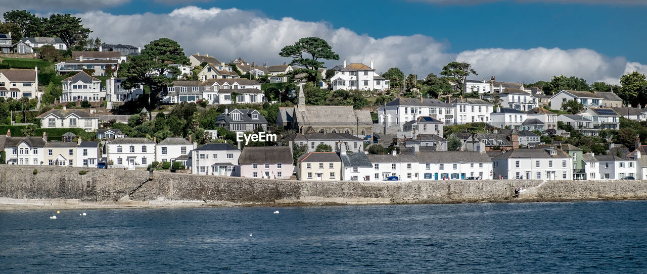 Houses in town by sea against sky