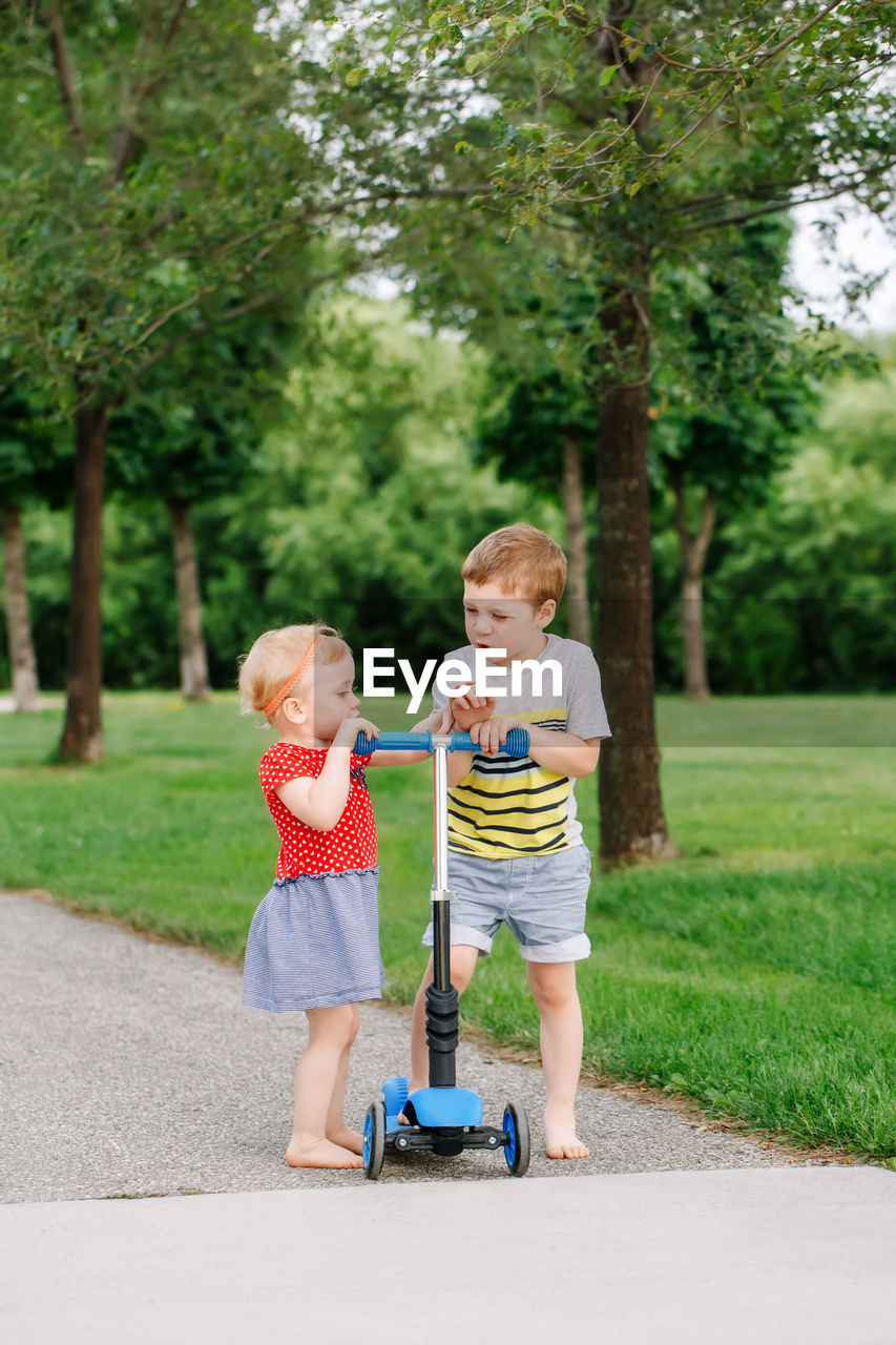 Siblings fighting for fight scooter on road at park