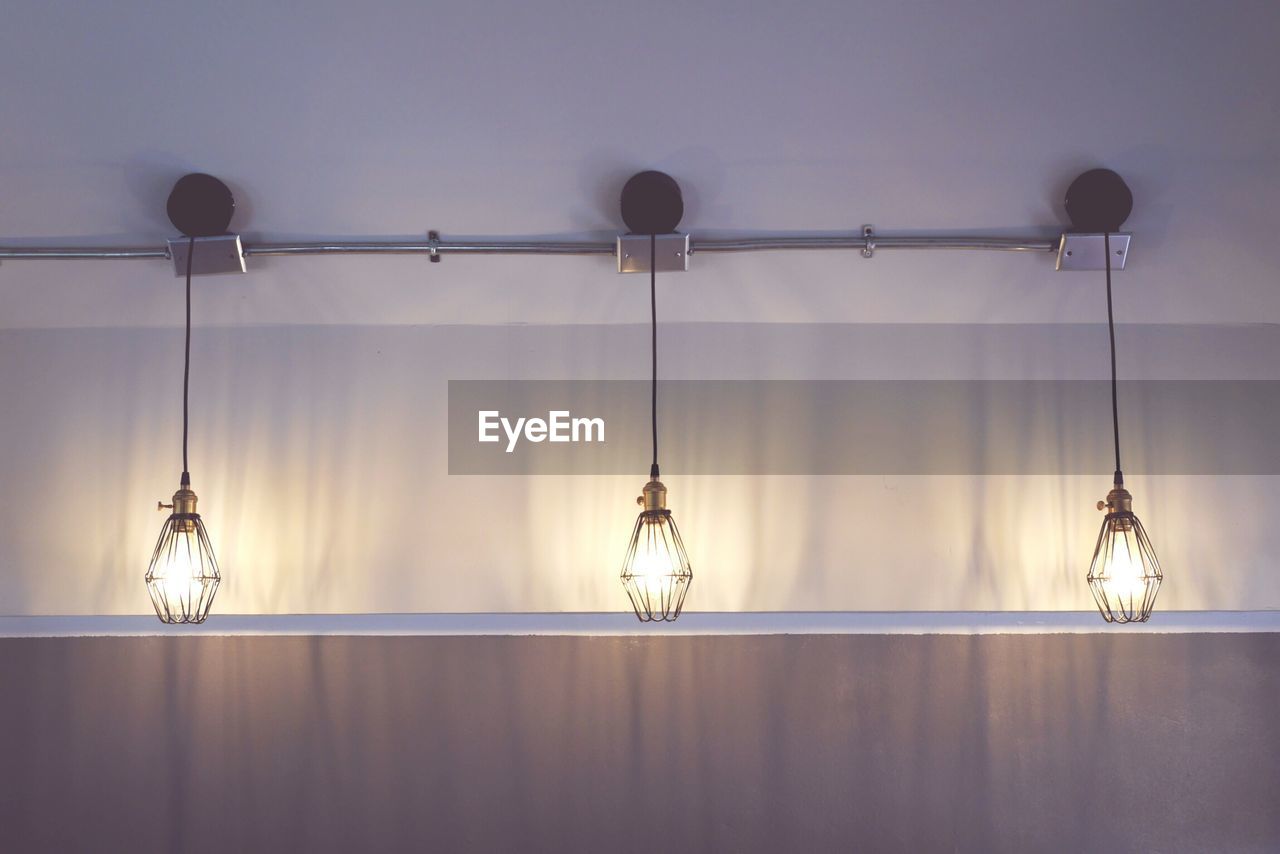 LOW ANGLE VIEW OF ILLUMINATED LIGHT BULBS HANGING ON CEILING