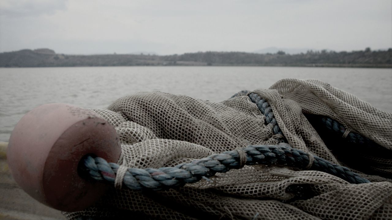 Close-up of fishing net with buoy and rope on pier