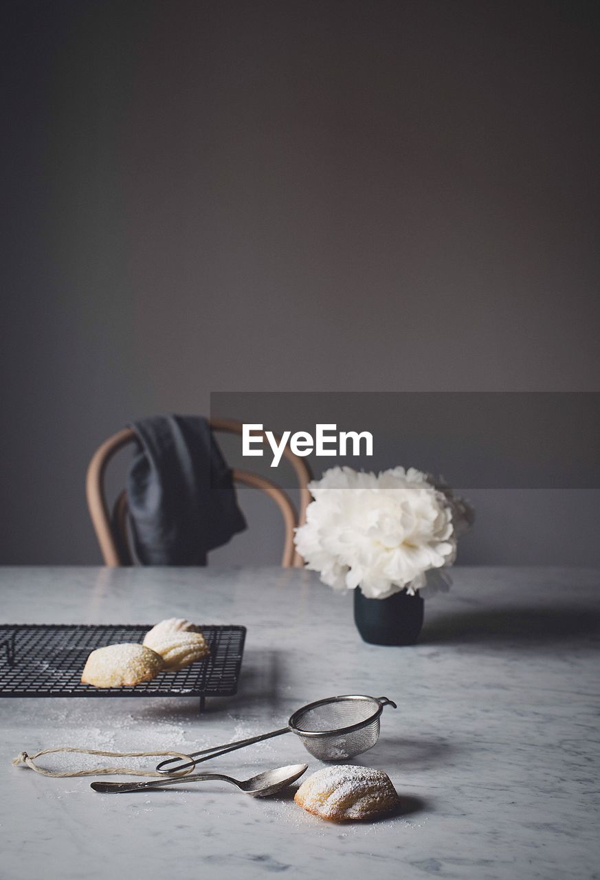 Close-up of cookies on metal grate by flower vase at table