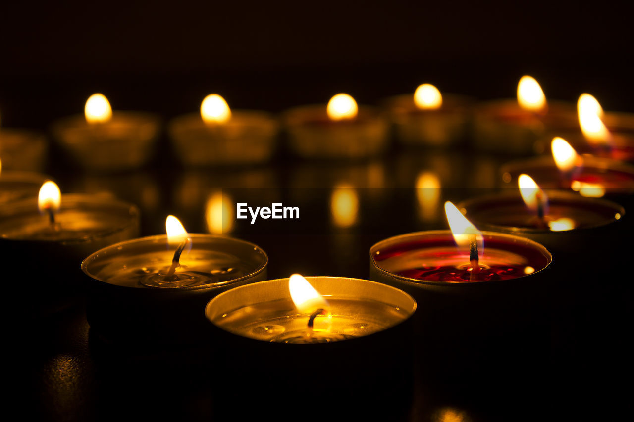 CLOSE-UP OF LIT CANDLES IN BUILDING