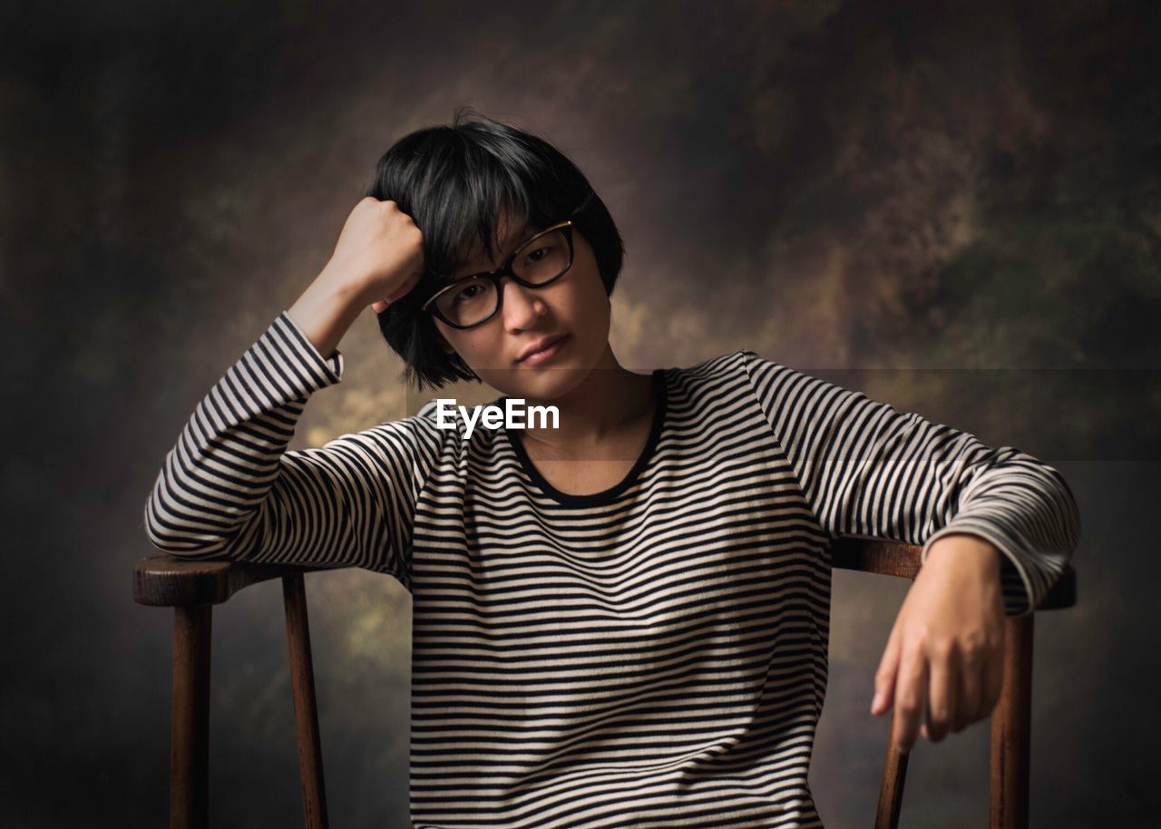 Portrait of depressed boy sitting on chair against wall