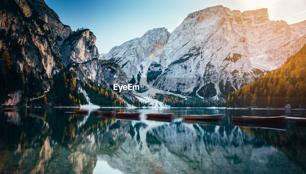 Boats in lake against snowcapped mountains