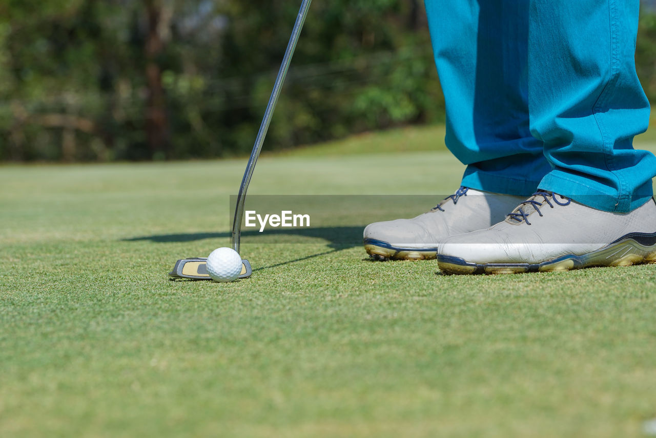 Low section of person relaxing on golf ball