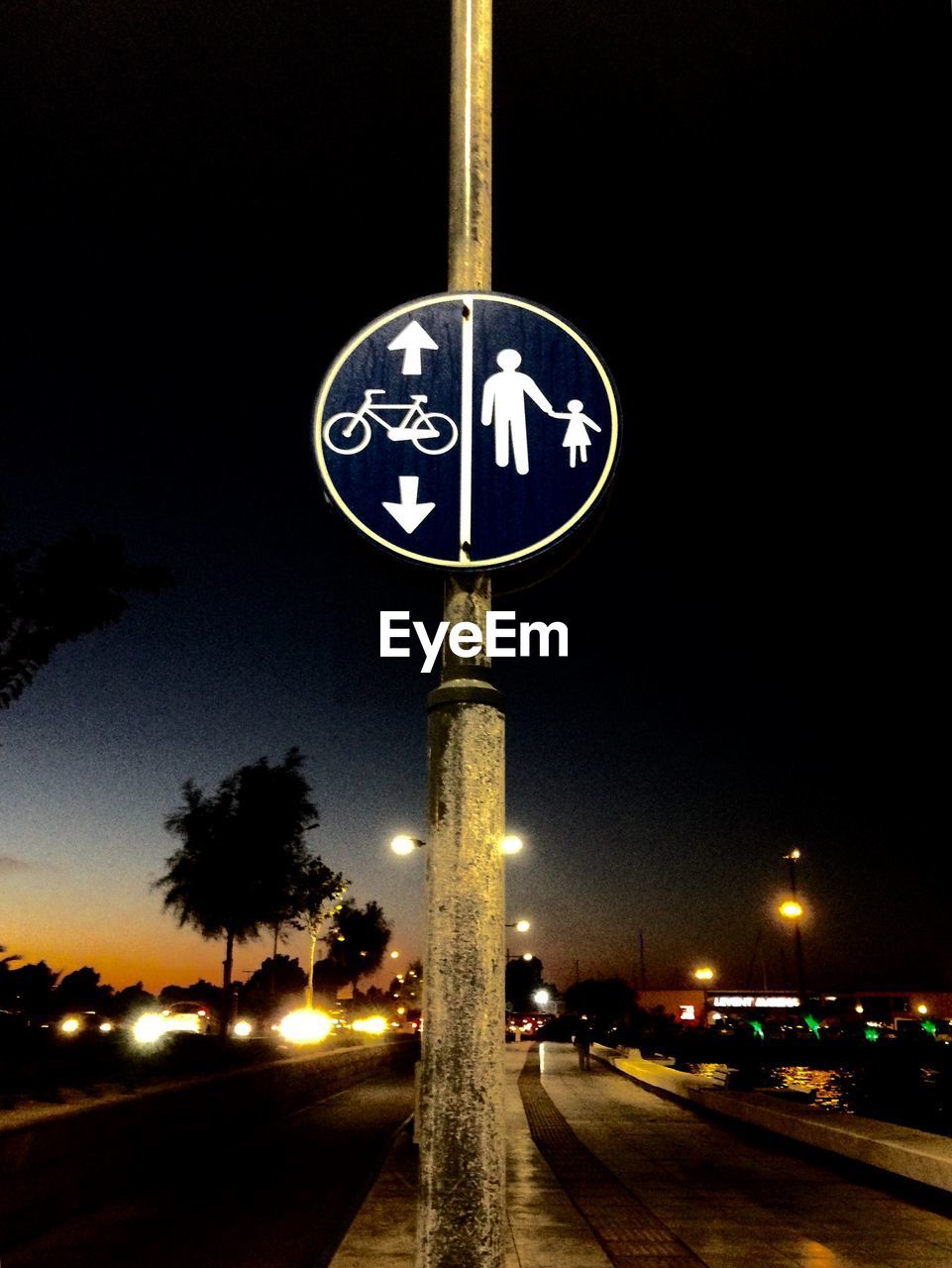 INFORMATION SIGN ON ILLUMINATED STREET LIGHT AT NIGHT