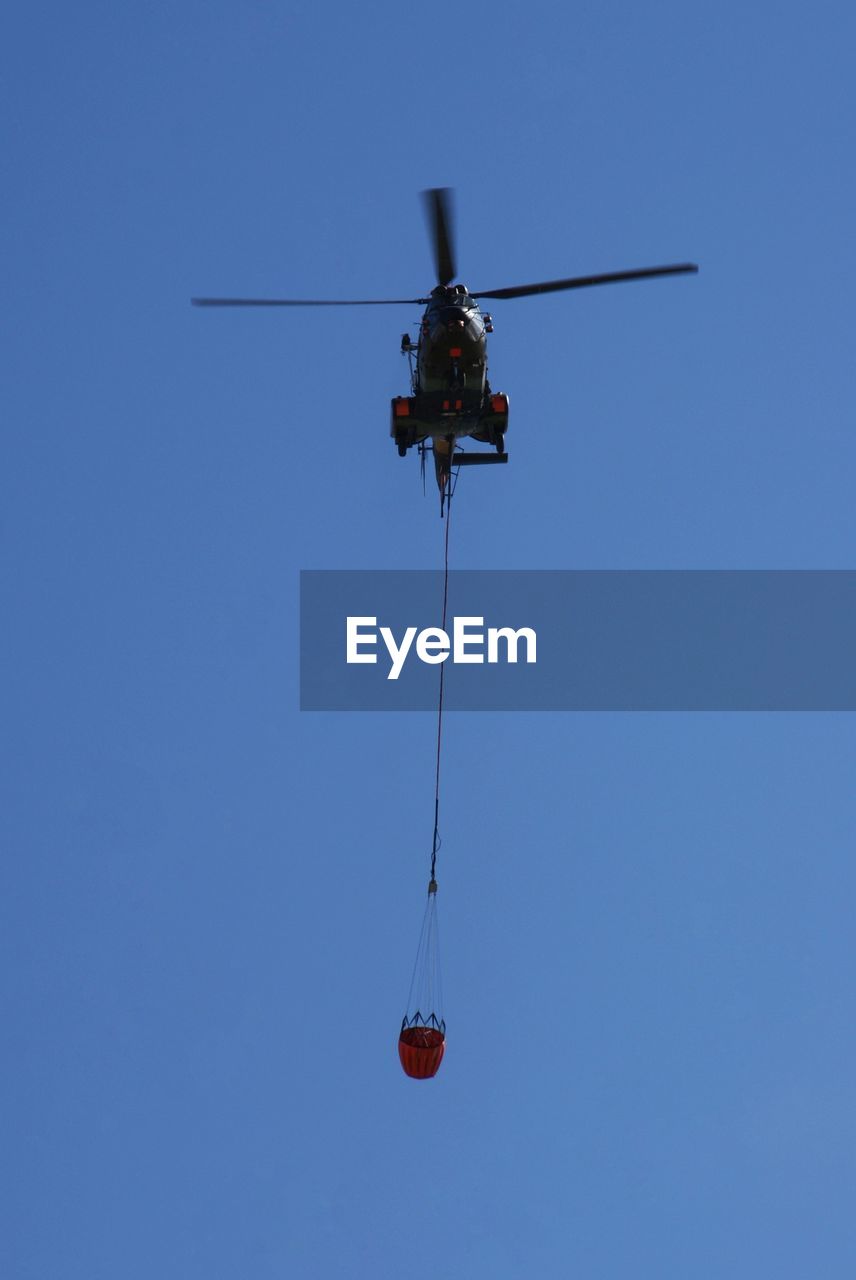 Low angle view of helicopter against clear blue sky