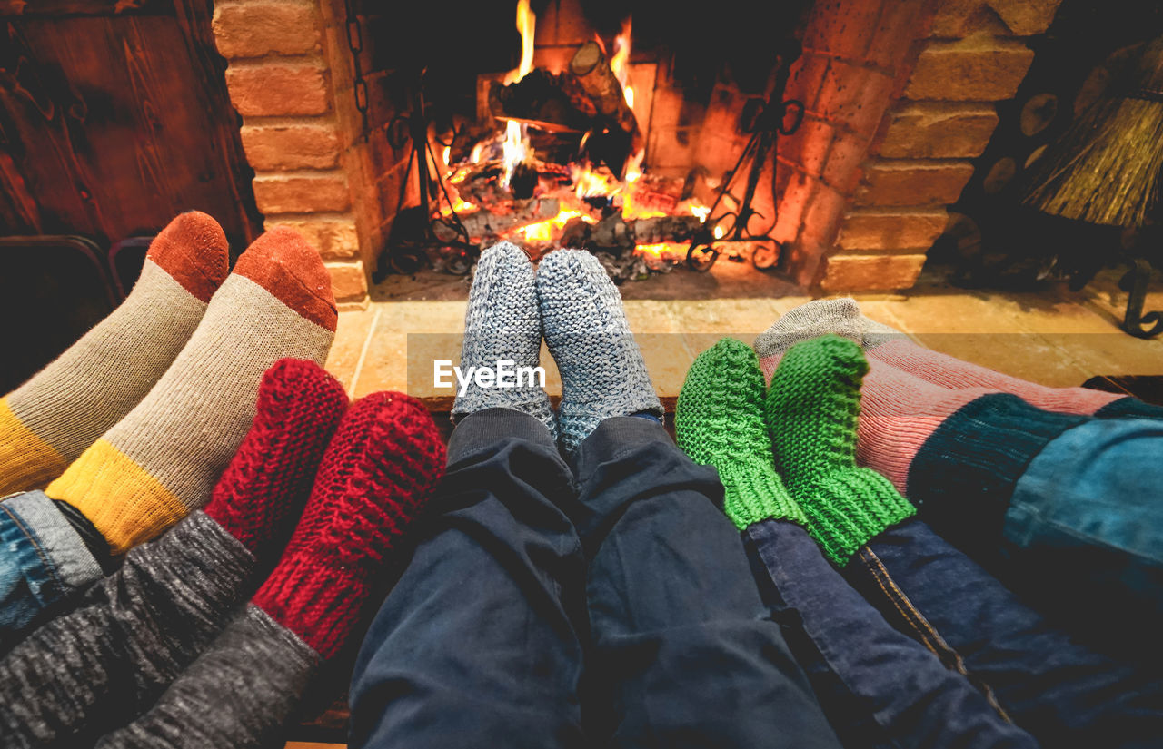 Low section of people wearing socks against fireplace