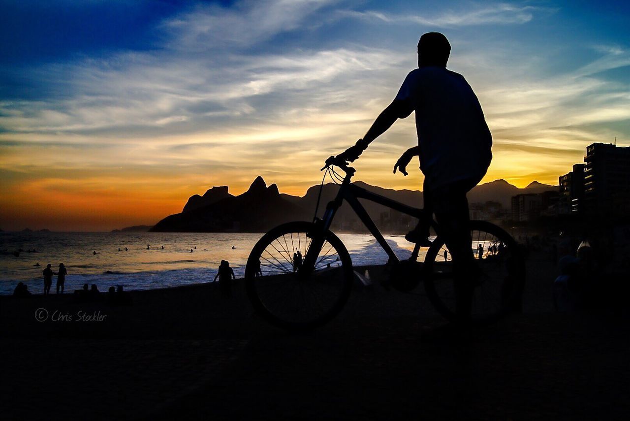 Silhouette of a tourist with a bicycle on the beach