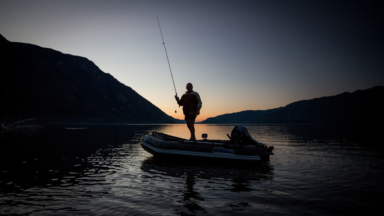 MAN IN BOAT ON SEA AGAINST SKY