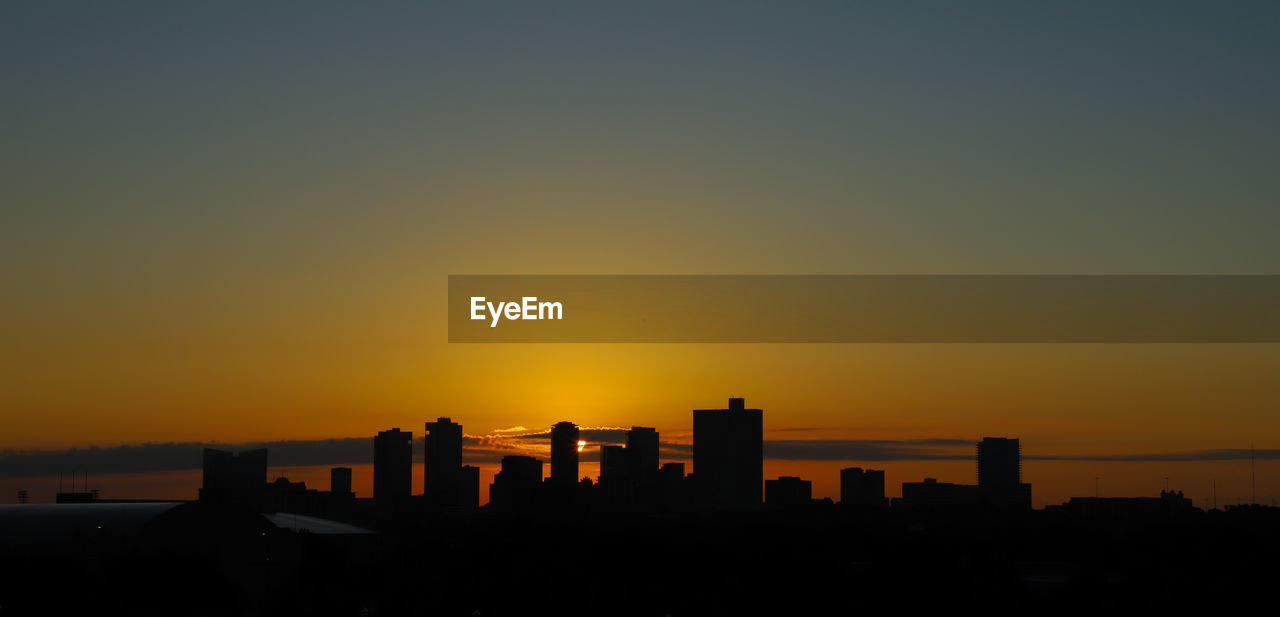 SILHOUETTE BUILDINGS AGAINST ORANGE SKY