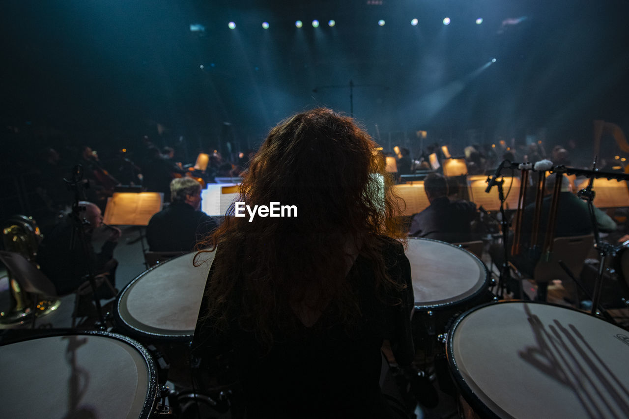 REAR VIEW OF WOMAN WATCHING MUSIC CONCERT