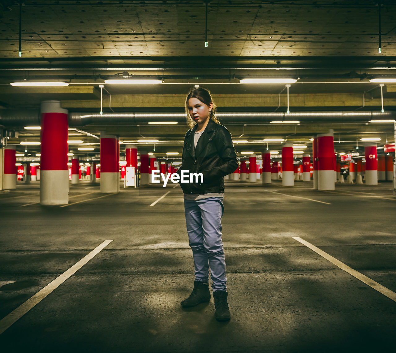 Portrait of girl standing at illuminated parking garage