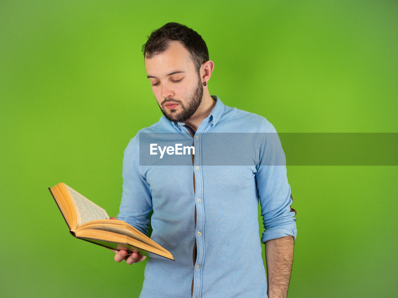 YOUNG MAN LOOKING AWAY WHILE STANDING AGAINST GRAY BACKGROUND