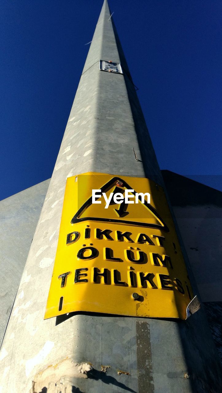 LOW ANGLE VIEW OF YELLOW SIGN ON BUILDING AGAINST BLUE SKY