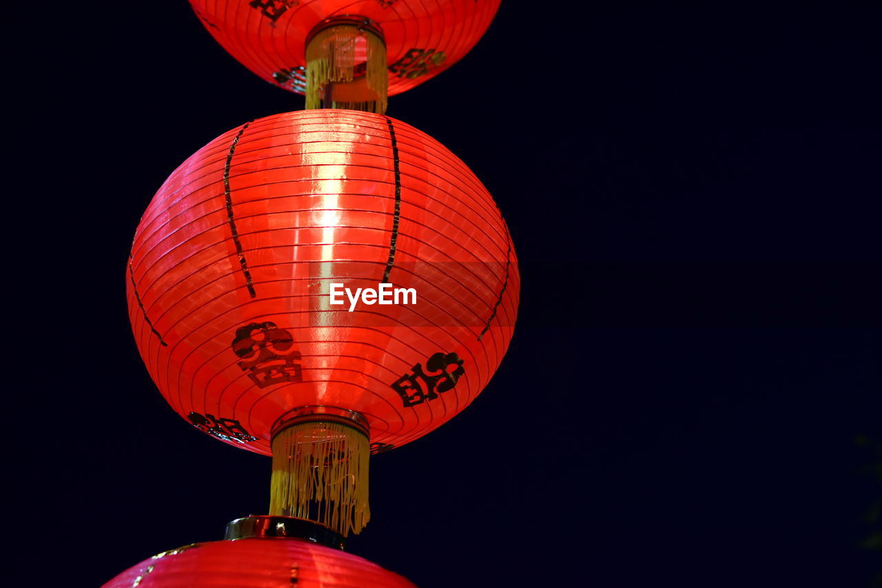 Low angle view of illuminated lantern against sky at night