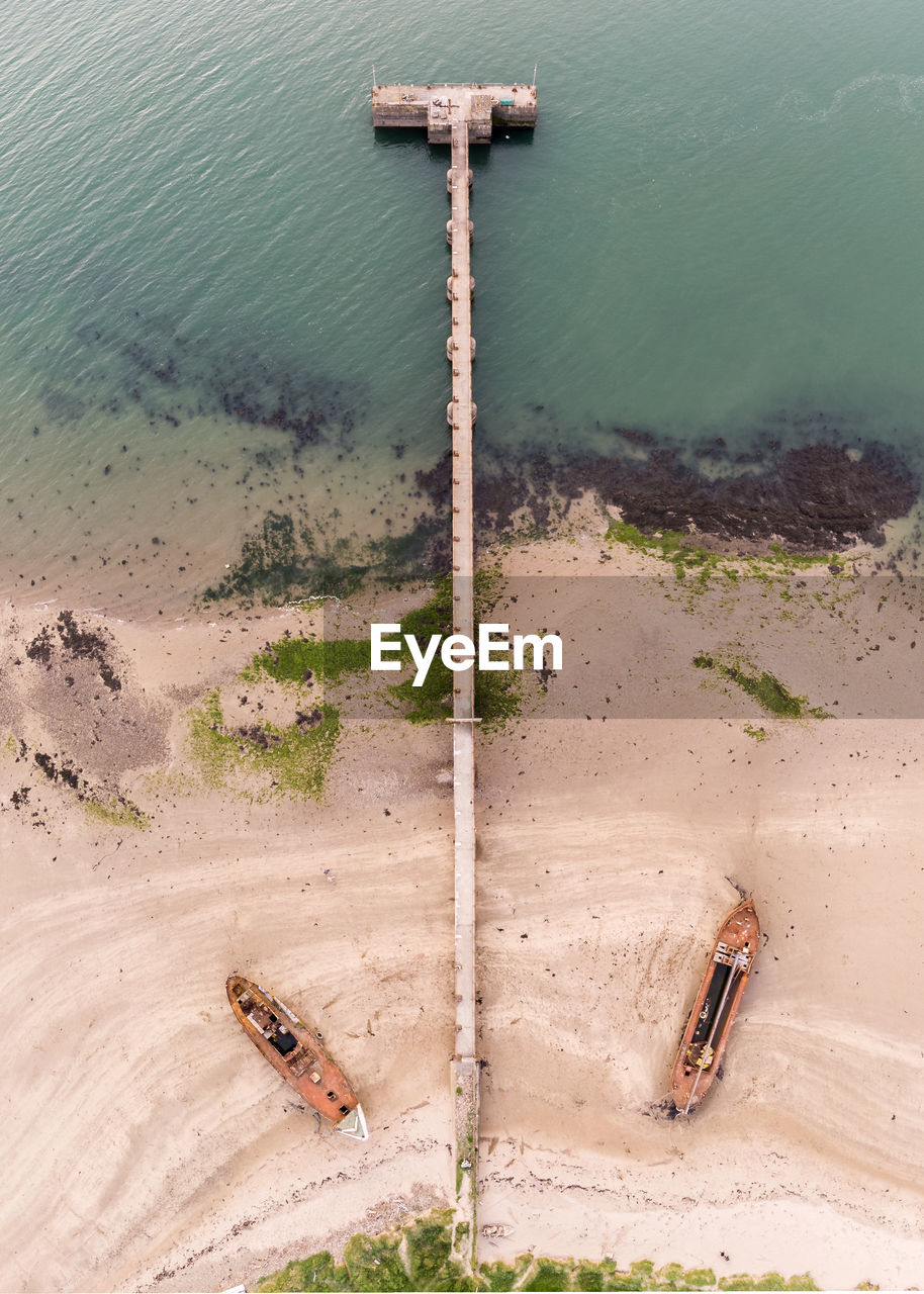 HIGH ANGLE VIEW OF RUSTY METAL ON SHORE