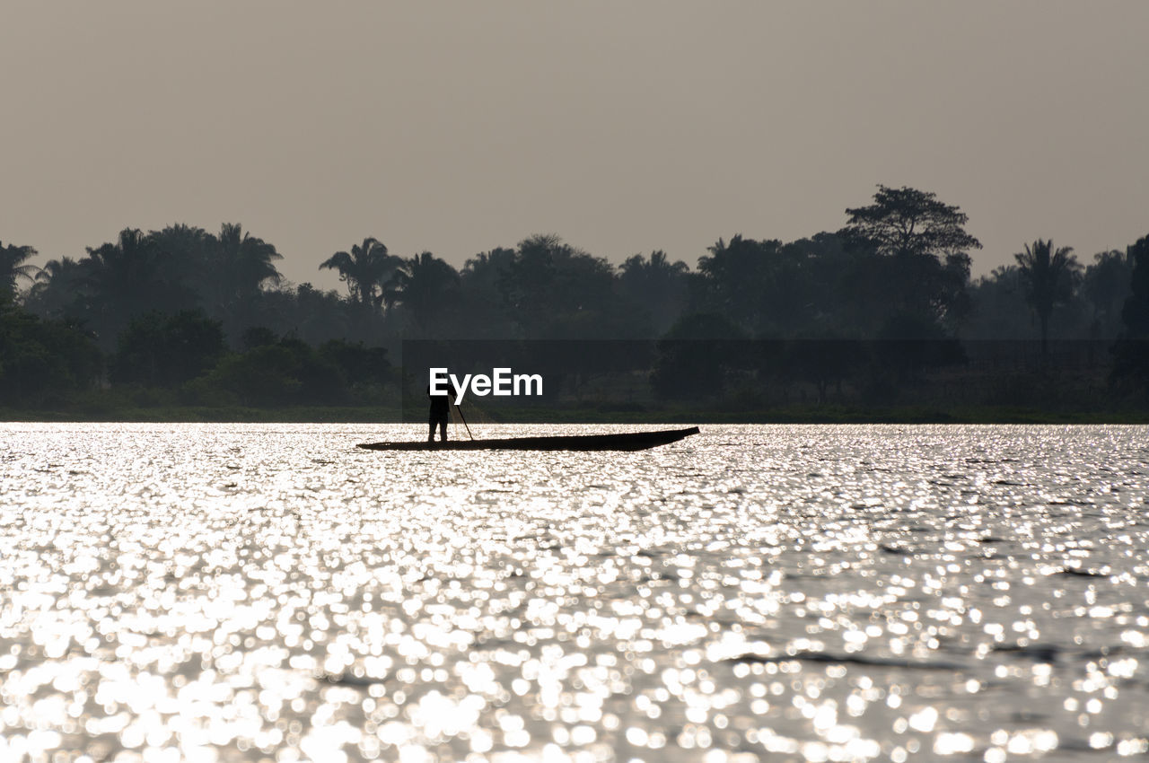 Silhouette fisherman sailing canoe in magdalena river