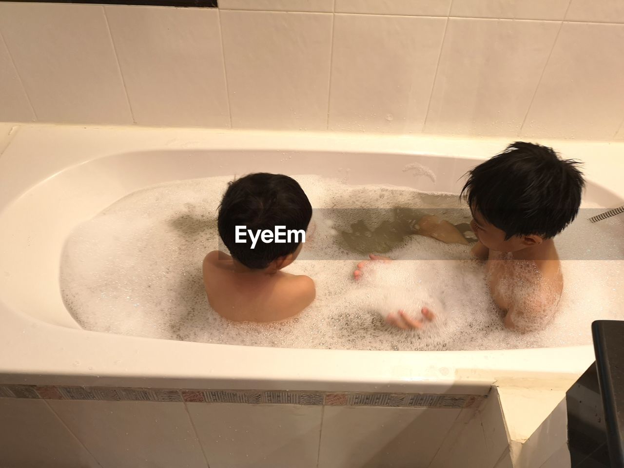 Siblings taking bath in tub at home