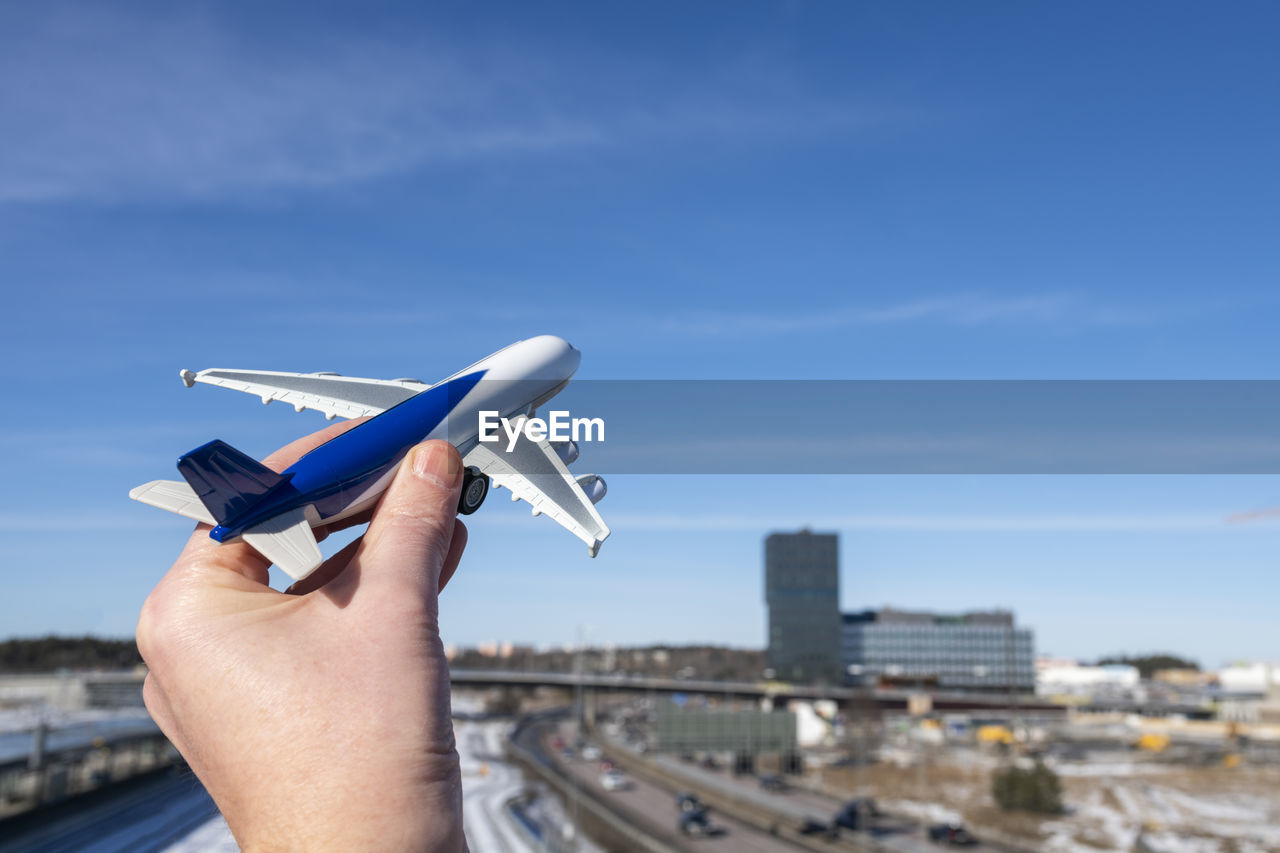 Man holding toy airplane against blue sky