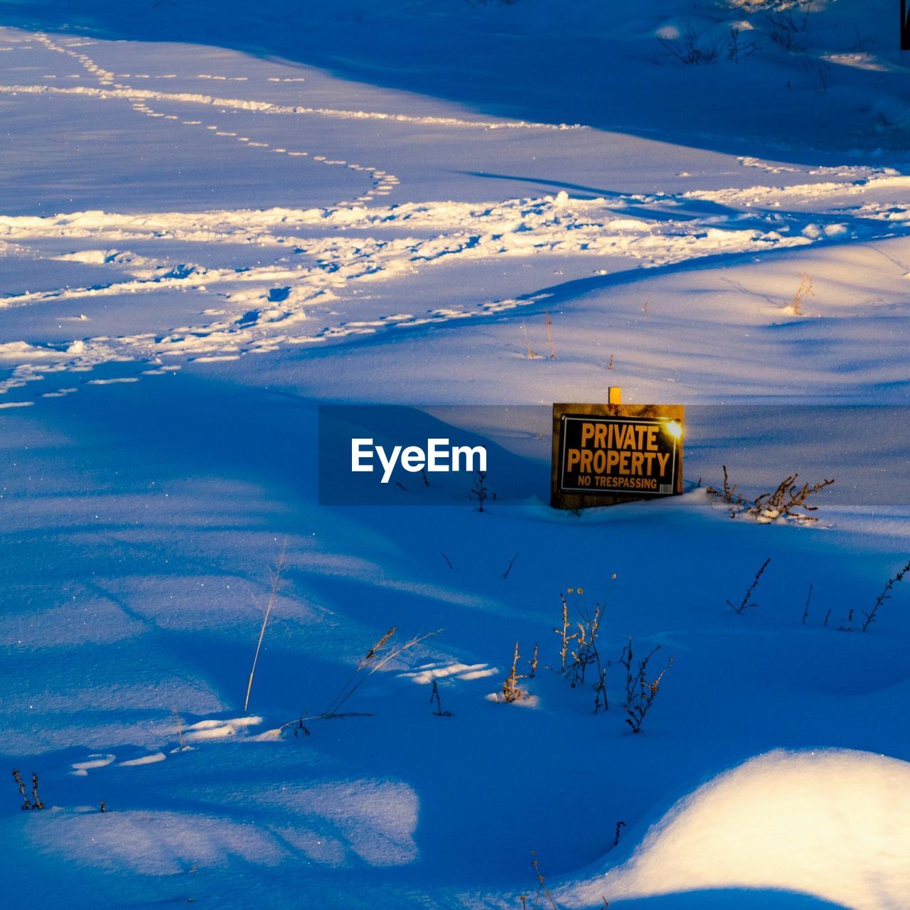 High angle view of information sign with text on snow covered landscape against sky