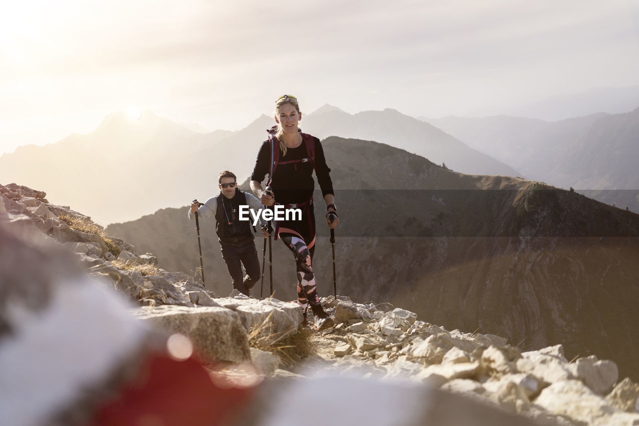 Sportsman and woman with hiking pole and backpack walking on mountain path of bschiesser at tyrol, austria